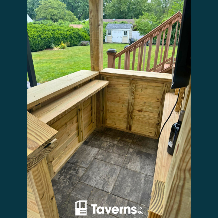 Wooden outdoor seating area with a view of a garden and house.