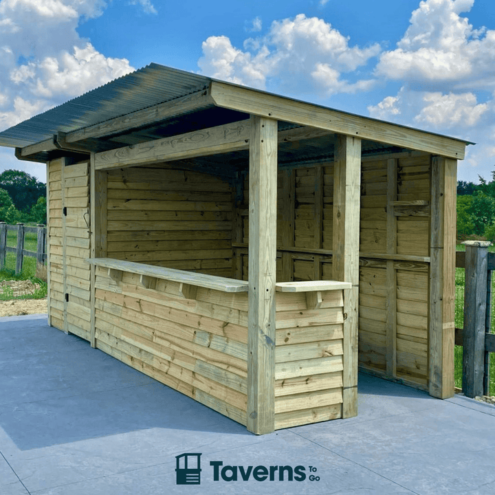 Wooden outdoor shelter with a roof, set against a blue sky with clouds.