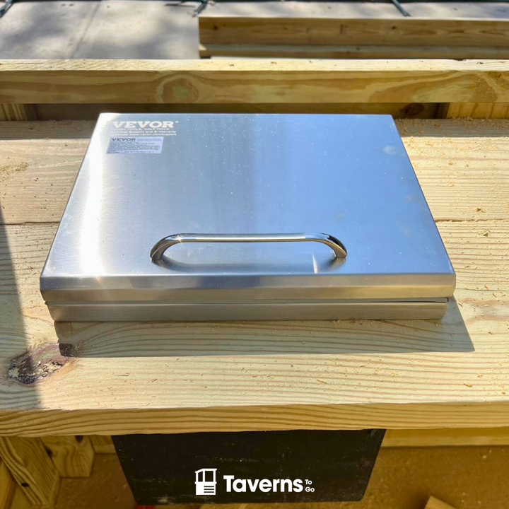 Stainless steel box with a handle on a wooden surface, branded &