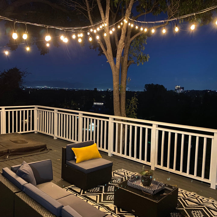 Outdoor patio with string lights, furniture, and a cityscape view at night.