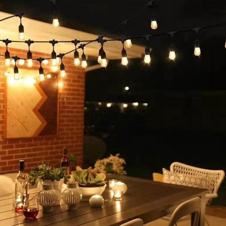 Outdoor patio setting with string lights, table, chairs, and decorative items.