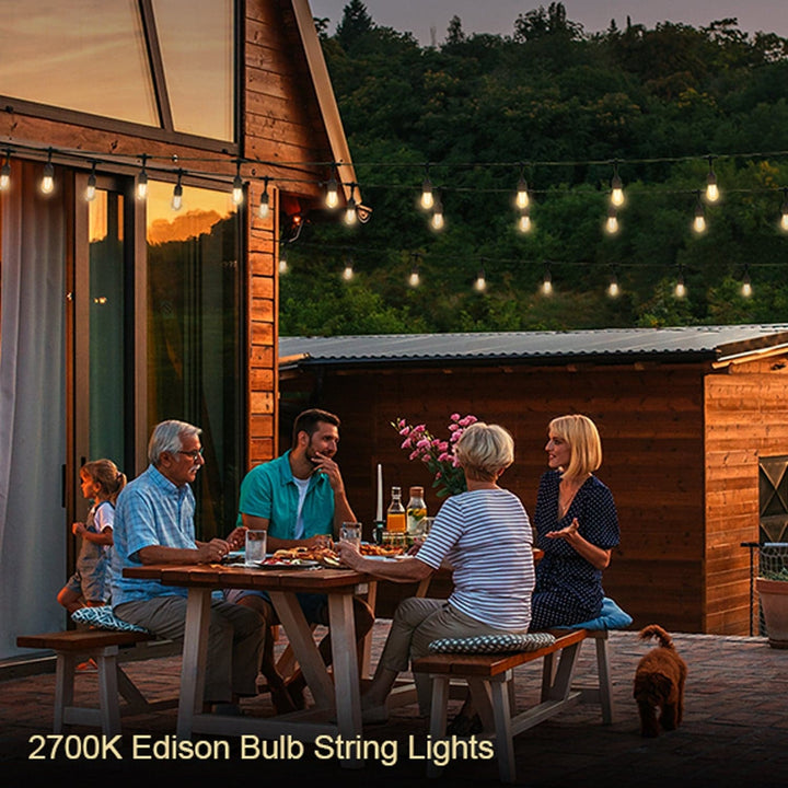 Family enjoying a meal outdoors with Edison bulb string lights illuminating the scene.