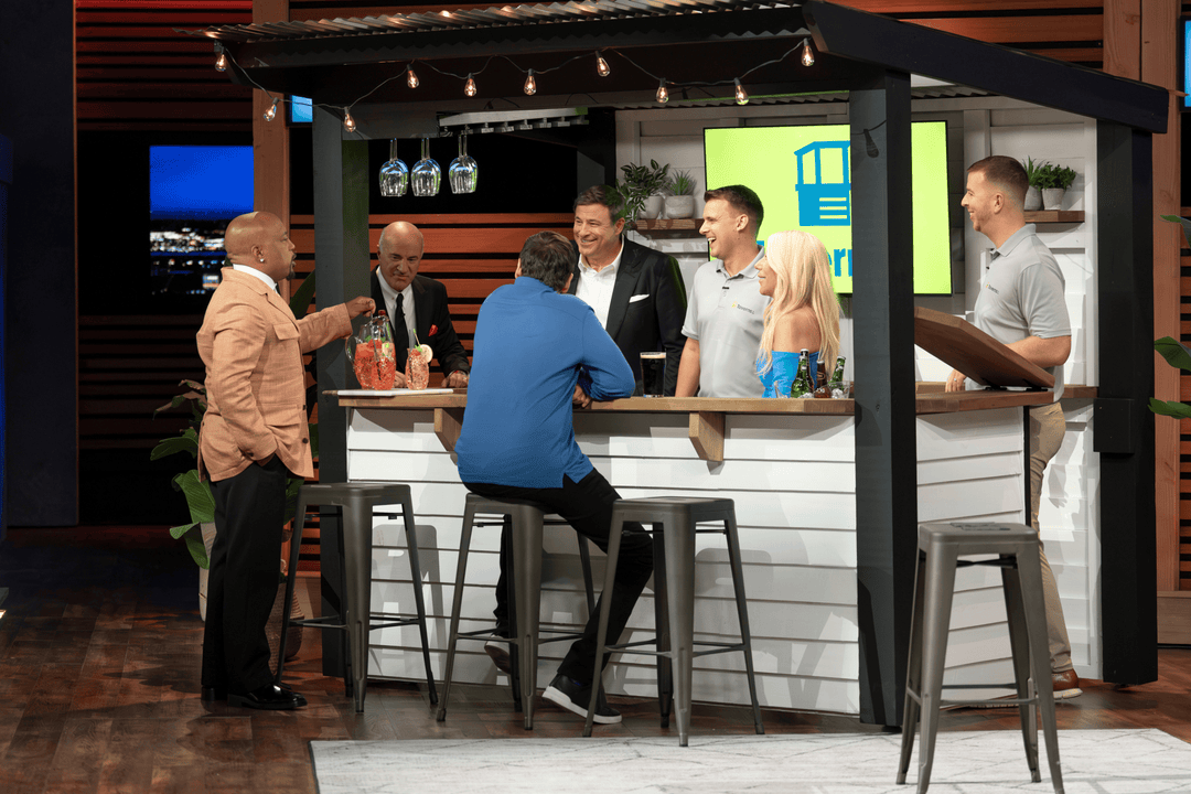 People gathered around a small bar area with stools and a counter.
